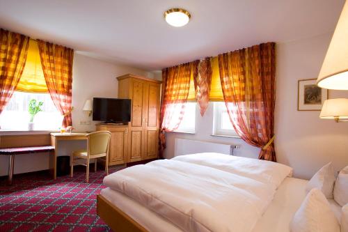 a bedroom with a bed and a desk and a television at Hotel Traube in Stuttgart