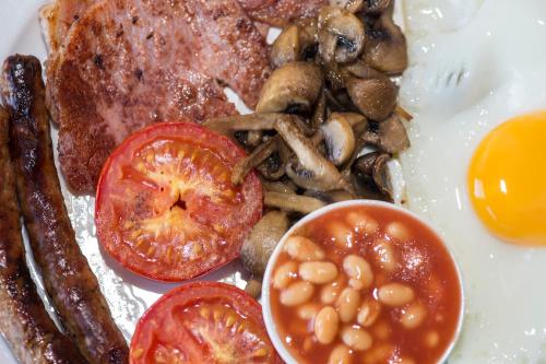 a plate of food with eggs sausage beans and tomatoes at Spanhoe Lodge in Harringworth