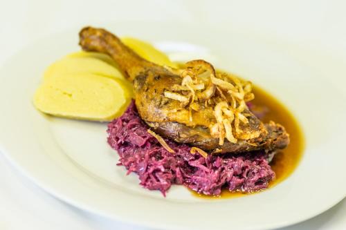 a plate of food with a chicken with sauce and purple cabbage at Hotel Kraví Hora in Bořetice