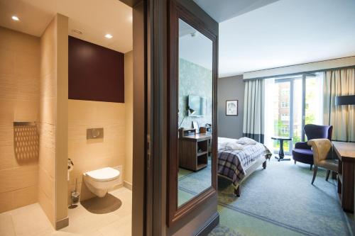 un bagno con servizi igienici e un letto in una camera. di Aspria Hamburg Uhlenhorst ad Amburgo