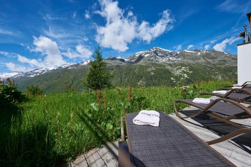 a table and chairs in a field with a mountain at Alpenhotel Laurin in Hochgurgl
