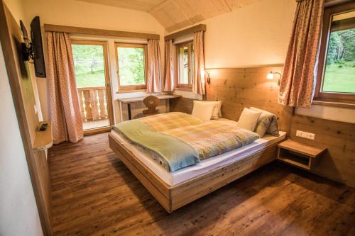 a bedroom with a bed in a room with windows at Rössingerhof in Ramsau am Dachstein