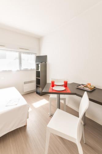 un salon avec une table et une chaise dans l'établissement City Résidence Nantes La Chantrerie, à Nantes