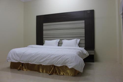 1 dormitorio con 1 cama grande y cabecero de madera en Rayanat Abha Aparthotel, en Abha