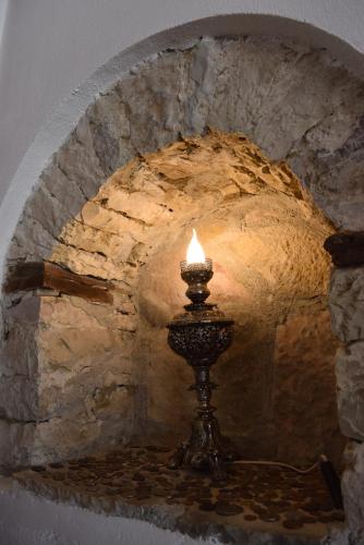 a candle in front of a stone wall at Hotel Gjirokastra in Gjirokastër