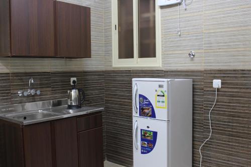a kitchen with a white refrigerator and a sink at Rayanat Abha Aparthotel in Abha