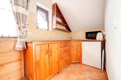 a kitchen with wooden cabinets and a refrigerator at Solny - Resort w Bieszczadach in Cisna