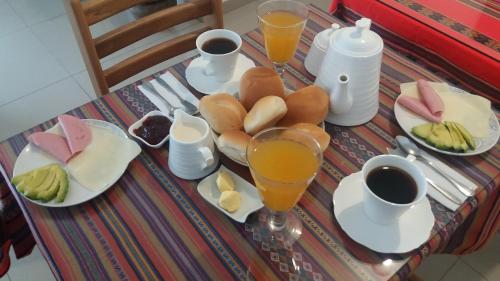 a table with plates of food and glasses of orange juice at La Maison de Lydia in Nazca
