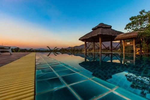 uma piscina de resort com um gazebo e água em Kuad Khon Thoe Pai Cottage em Pai