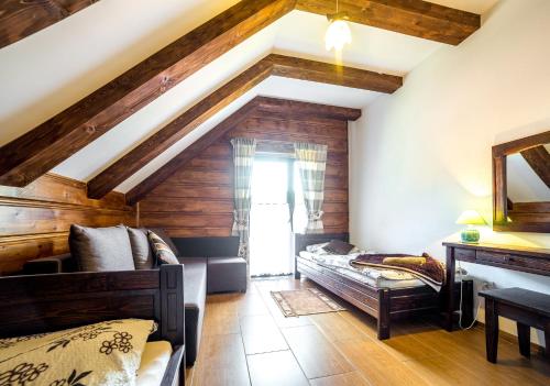 a bedroom with wooden walls and a ceiling with beams at Solny - Resort w Bieszczadach in Cisna