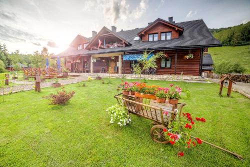 a house with flowers on the lawn in front of it at Solny - Resort w Bieszczadach in Cisna