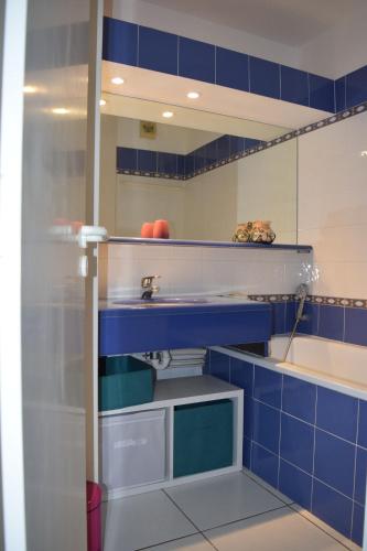 La salle de bains bleue et blanche est pourvue d'un lavabo et d'une baignoire. dans l'établissement Villa le Hameau - Cap Esterel (Agay), à Saint-Raphaël