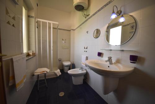 ein Badezimmer mit Waschbecken, Toilette und Spiegel in der Unterkunft Hotel La Villa in Corigliano Calabro