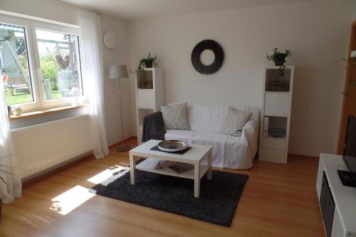 ein Wohnzimmer mit einem weißen Sofa und einem Tisch in der Unterkunft Ferienwohnung Familie Igel in Horgenzell