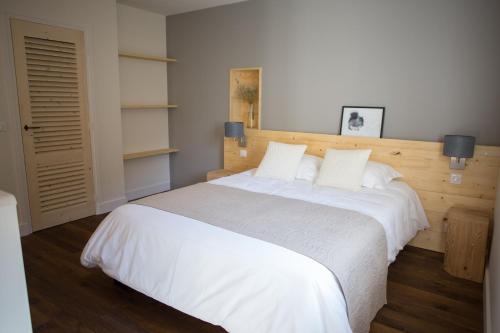 Un dormitorio con una gran cama blanca con dos almohadas. en La Grange aux Ecureuils, en Levernois