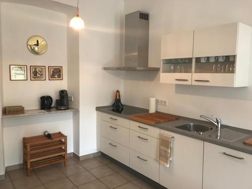 kuchnia z białymi szafkami i zlewem w obiekcie Herrenhaus - Weingut Freiherr v. Landenberg w mieście Ediger-Eller