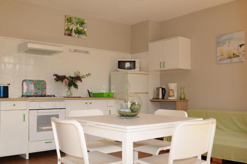 a white kitchen with a white table and white chairs at Au Songe du Valier- Chalets in Seix