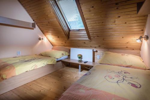 two beds in a room with wooden walls and a window at Mária Kičáková TATRY MKS in Štrba