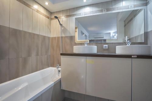 une salle de bain avec deux lavabos, une baignoire et un miroir dans l'établissement Capucine Duplex, à La Ciotat