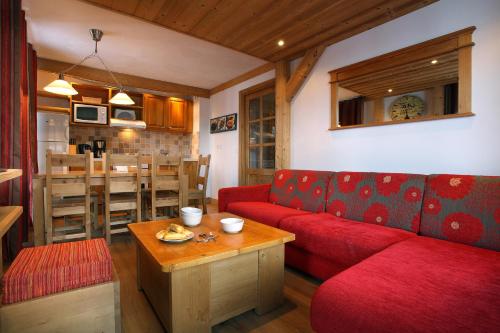 uma sala de estar com um sofá vermelho e uma mesa em Chalet des Neiges : La Cime Des Arcs em Arc 2000