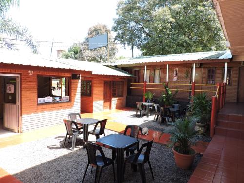 un patio avec des tables et des chaises en face d'un bâtiment dans l'établissement Hostel Park Iguazu, à Puerto Iguazú