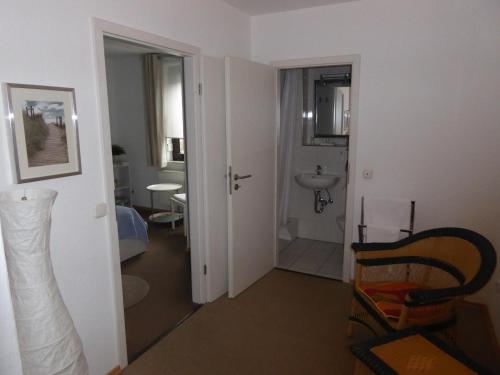 a room with a bathroom with a sink and a chair at Hotel Garni-Tell in Siegen