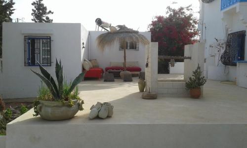 a white house with a patio with a potted plant at Menzel Churasco Djerba in Aghīr