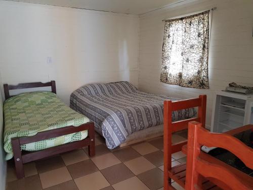 a bedroom with a bed and a chair and a window at Turismo el Bosque in Pichilemu