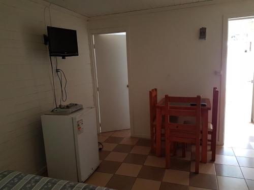 a room with a refrigerator and a table and a television at Turismo el Bosque in Pichilemu