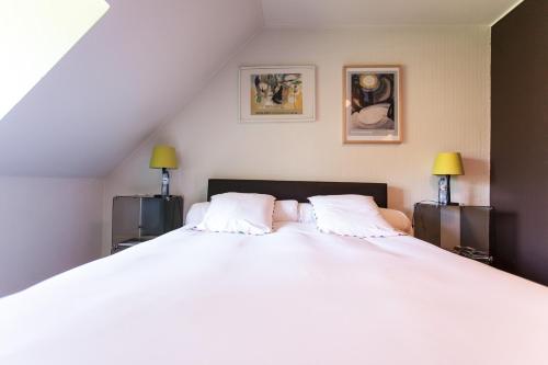 B&B Le Bois Dormant في سبا: غرفة نوم بسرير ابيض كبير ومصباحين