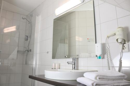 ein weißes Badezimmer mit einem Waschbecken und einem Spiegel in der Unterkunft City Hotel Journal in Wolfsburg