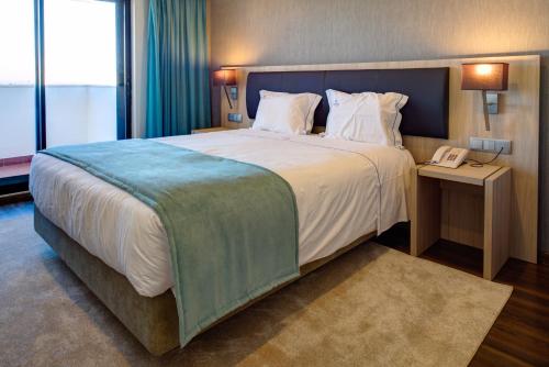 a large bed in a hotel room with a telephone at VIP Executive Zurique Hotel in Lisbon