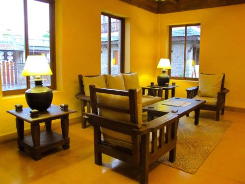 a living room with a table and chairs and windows at Temple Tree Resort & Spa, Pokhara in Pokhara