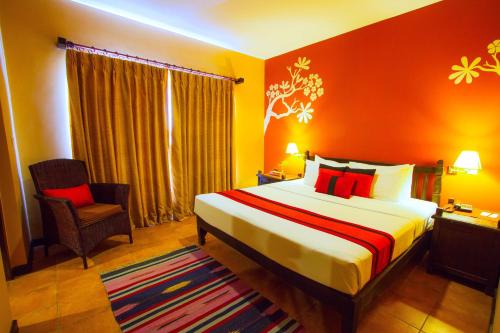 a bedroom with a bed and a chair in a room at Temple Tree Resort & Spa, Pokhara in Pokhara