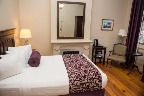 um quarto com uma cama com lareira e um espelho em Inn on St. Peter, a French Quarter Guest Houses Property em Nova Orleans