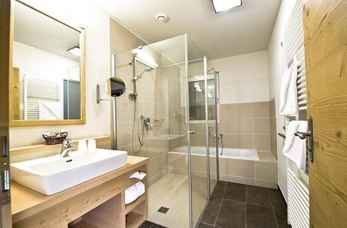 a bathroom with a sink and a glass shower at Hotel Feldwebel in Söll