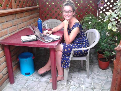 a woman sitting at a table with a laptop at Hostel Julieta in Rivas