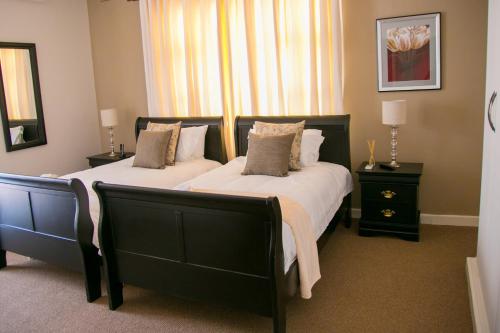 a bedroom with two beds and two night stands at Jacaranda in Harare