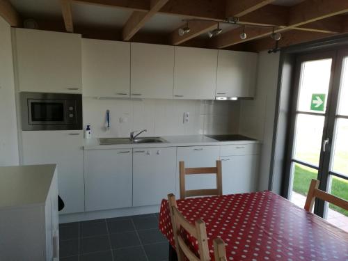 uma cozinha com armários brancos e uma mesa com uma toalha de mesa vermelha em Wenduine zeehuisje 16 em Wenduine
