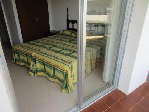 ein Schlafzimmer mit einem Bett mit einer grünen und gelben Decke in der Unterkunft Apartament Medes Parc I 4 6 inmoestartit in L'Estartit