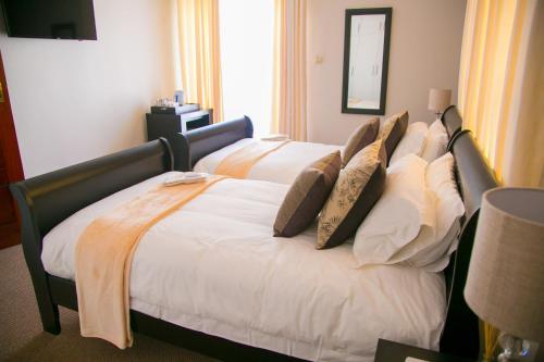 a bed with pillows on it in a hotel room at Jacaranda in Harare