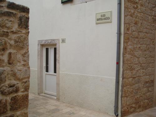 een wit gebouw met een deur en een bord erop bij Mirina in Stari Grad