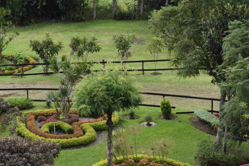 a garden with flowers and trees and a fence at Hotel Rancho Constanza & Cabañas de la Montaña in Constanza