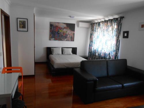 a living room with a bed and a couch at Sinos Rio Tinto in Campainha