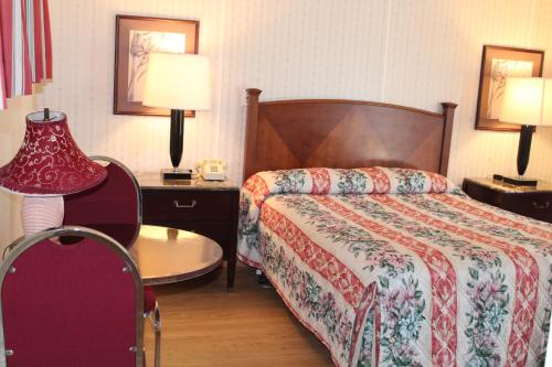 a hotel room with a bed and a table and lamps at Royale Coach Motor Lodge in Hampton