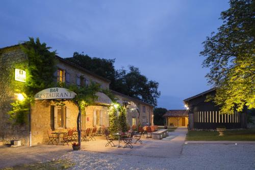 a building with tables and chairs in front of it at Logis L'Auberge de Larressingle in Larressingle