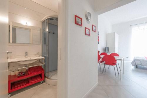 a white bathroom with a sink and a red chair at A due passi dal centro - Bari Policlinico in Bari