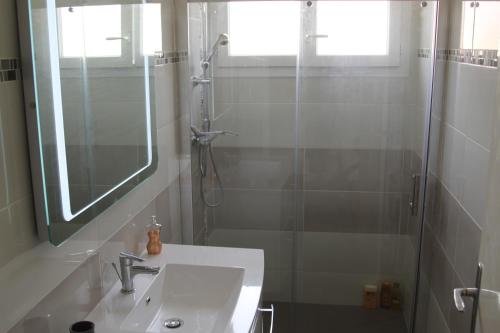 a bathroom with a sink and a shower with a mirror at Appartement lumineux et Agréable 6 Personnes in Saint Malo