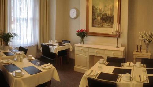 a restaurant with white tables and chairs and a clock at Carena House in Canterbury