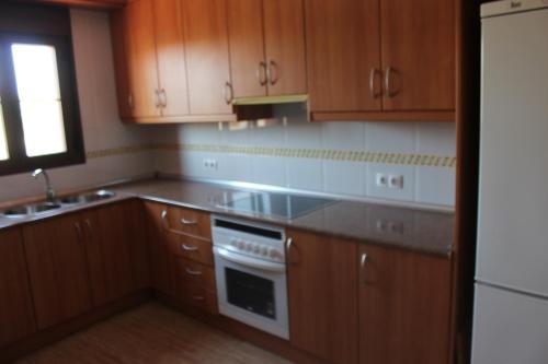 uma cozinha com armários de madeira e um forno com placa de fogão em Apartamentos Turísticos Edificio del Pino em Sorbas